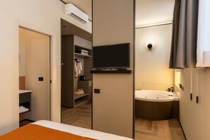 A modern hotel room with a bed, a television, a shower area, and a walk-in closet. - Jacuzzi Relax – San Giovanni (Rome)