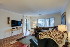 A living room with a flat-screen TV, a sofa, a coffee table, and a patterned rug. - Relaxing condo with pool, balcony (Hilton Head)
