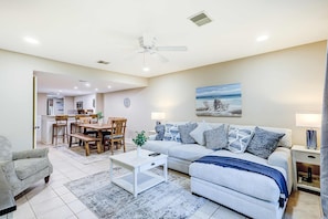 A living room with a sofa, coffee table, and dining area. - Charming villa with pool, balcony, full kitchen, central AC, & washer dryer (Hilton Head)