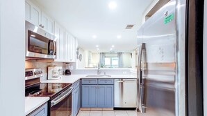 A modern kitchen with stainless steel appliances, white cabinets, and a large island.
