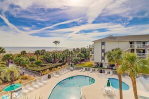 A pool area with lounge chairs, a pool, and a view of the beach. - Beach-view condo in oceanfront complex with outdoor pool, beach access & balcony (Hilton Head)