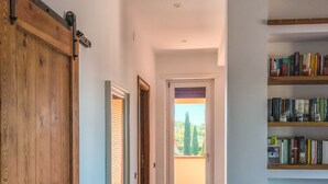 A hallway with a wooden door, a bookshelf, and a view through a glass door. - Il Favoloso Mondo di Vale (Marino)