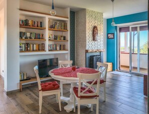 A cozy living room with a fireplace, bookshelves, a round table with chairs, and a television.