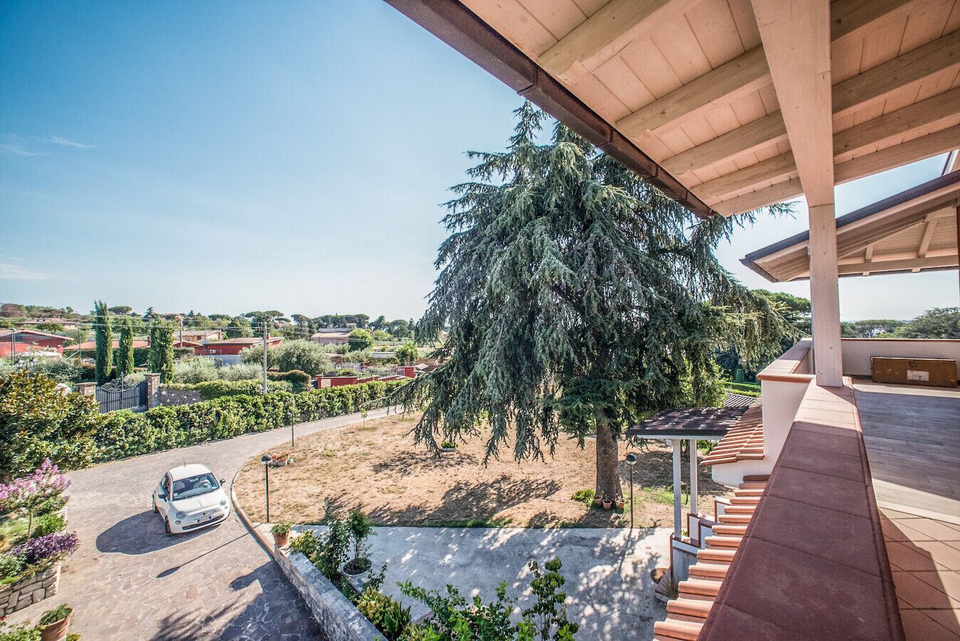 Une propriété résidentielle dotée d’un patio couvert, d’un grand arbre et d’une voiture garée.