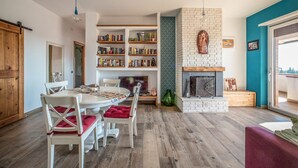 A modern living room with a fireplace, bookshelves, and a dining area with chairs. - Il Favoloso Mondo di Vale (Marino)