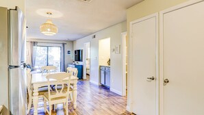 A kitchen with a dining table and chairs, a refrigerator, and a hanging light fixture. - End unit, 3rd floor Apartment near beach with balcony, pool, & tennis (Hilton Head)