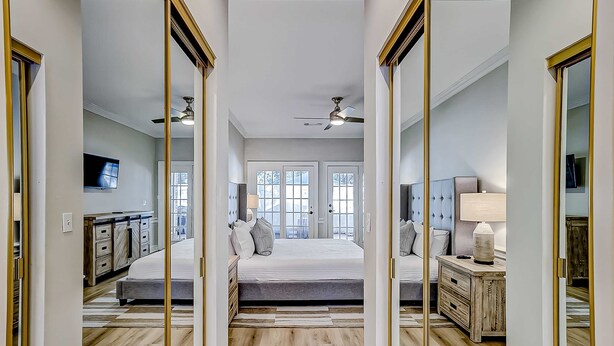 Un dormitorio con cama, mesitas de noche, espejo y ventilador de techo.