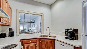 Una cocina moderna con armarios de madera, horno empotrado, cafetera y un espejo grande sobre el lavabo.