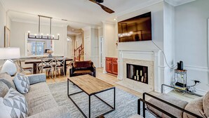 Amplia sala de estar con chimenea, un comedor y una cocina al fondo.