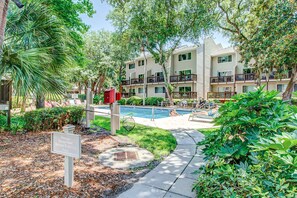 A residential building with a swimming pool, surrounded by greenery and a sign instructing to rinse feet before entering the pool. - Fun & bright beach getaway with pool, easy beach access & pond view (Hilton Head)