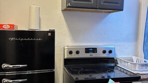A kitchen with a black Frigidaire refrigerator, a stove, and a microwave. -  1-bedroom Temple near train and buses (Philadelphia)