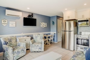 A compact kitchen with a refrigerator, stove, and wall-mounted TV. - Oceanfront resort condo with WiFi, balcony, pool, grills, & beach access (Hilton Head)
