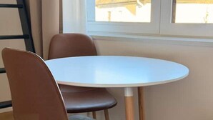 Une table ronde avec un plateau blanc et des pieds en bois, entourée de quatre chaises marron.