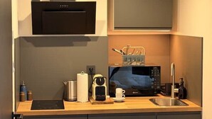 Une cuisine moderne équipée d’un four à micro-ondes, d’une machine à café et d’une bouilloire, le tout posé sur le plan de travail.