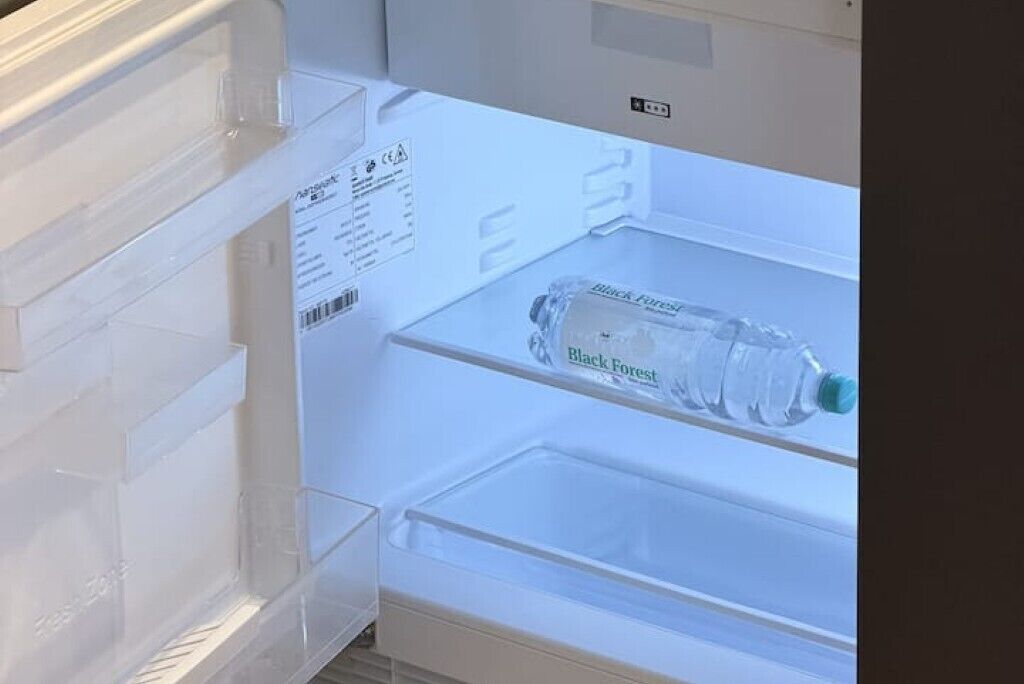 Een open koelkast met een waterfles met de tekst 'Black Forest' op het deurtje.