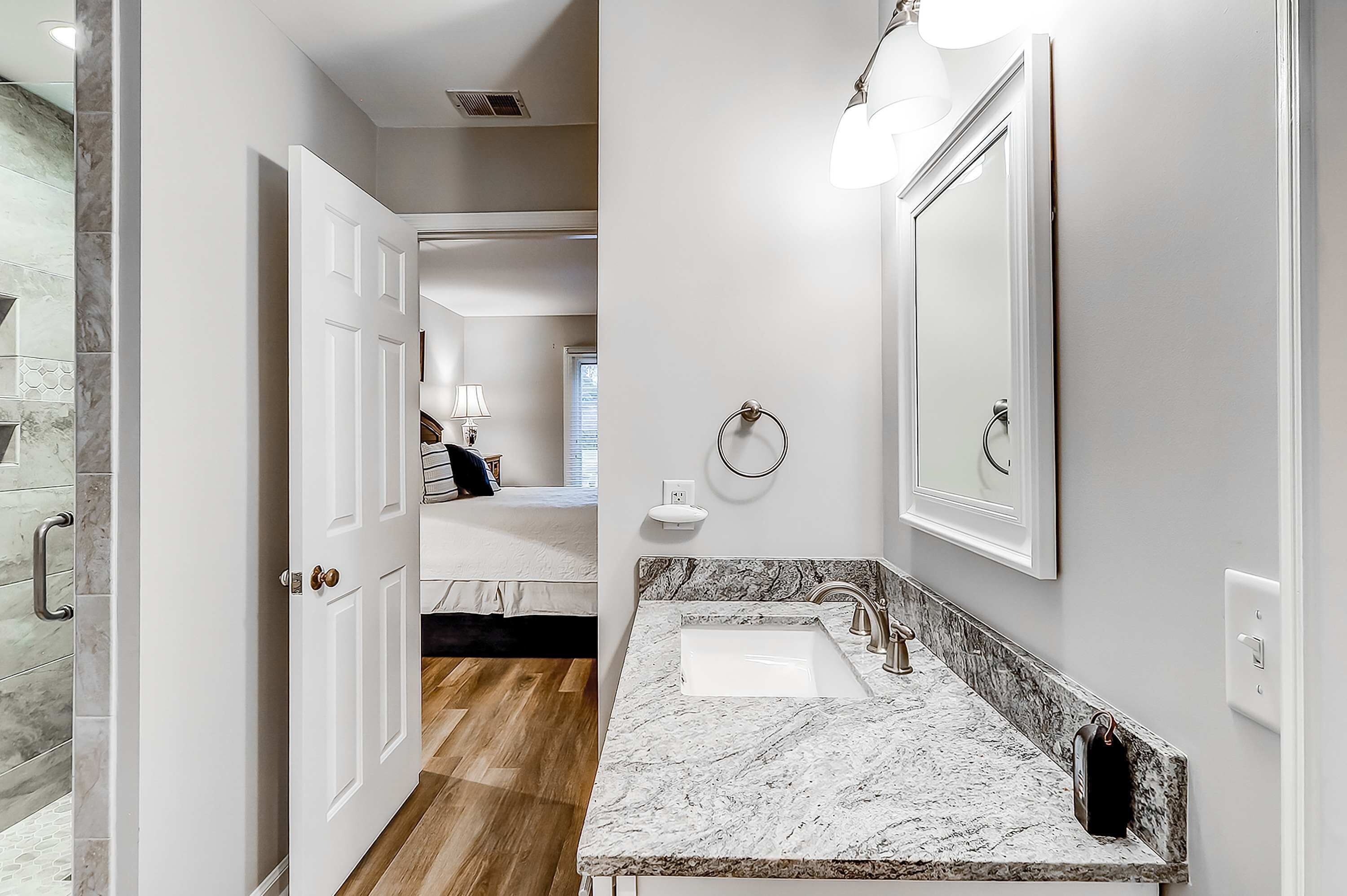 A bathroom with a marble sink, a large mirror, and a towel ring.