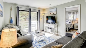 Ein Wohnzimmer mit einer Couch, einem Couchtisch, einem Fernseher und einer Lampe.