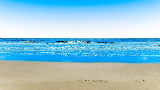 Ein Strand mit klarem, blauem Wasser und einem sandigen Ufer.