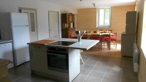 Una cocina compacta con horno integrado, un refrigerador y una zona de comedor con sillas y mesa de madera.