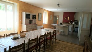 Un comedor con una mesa y sillas de madera, una zona de cocina con mostrador y una pared roja decorativa.