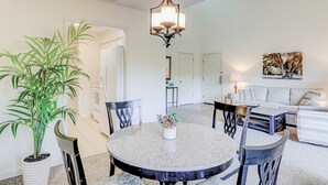 A dining area with a round table, chairs, a potted plant, and a chandelier. - Snowbird Friendly villa with Golf View, Patio, Shared Pool, Tennis, AC, WiFi (Hilton Head)