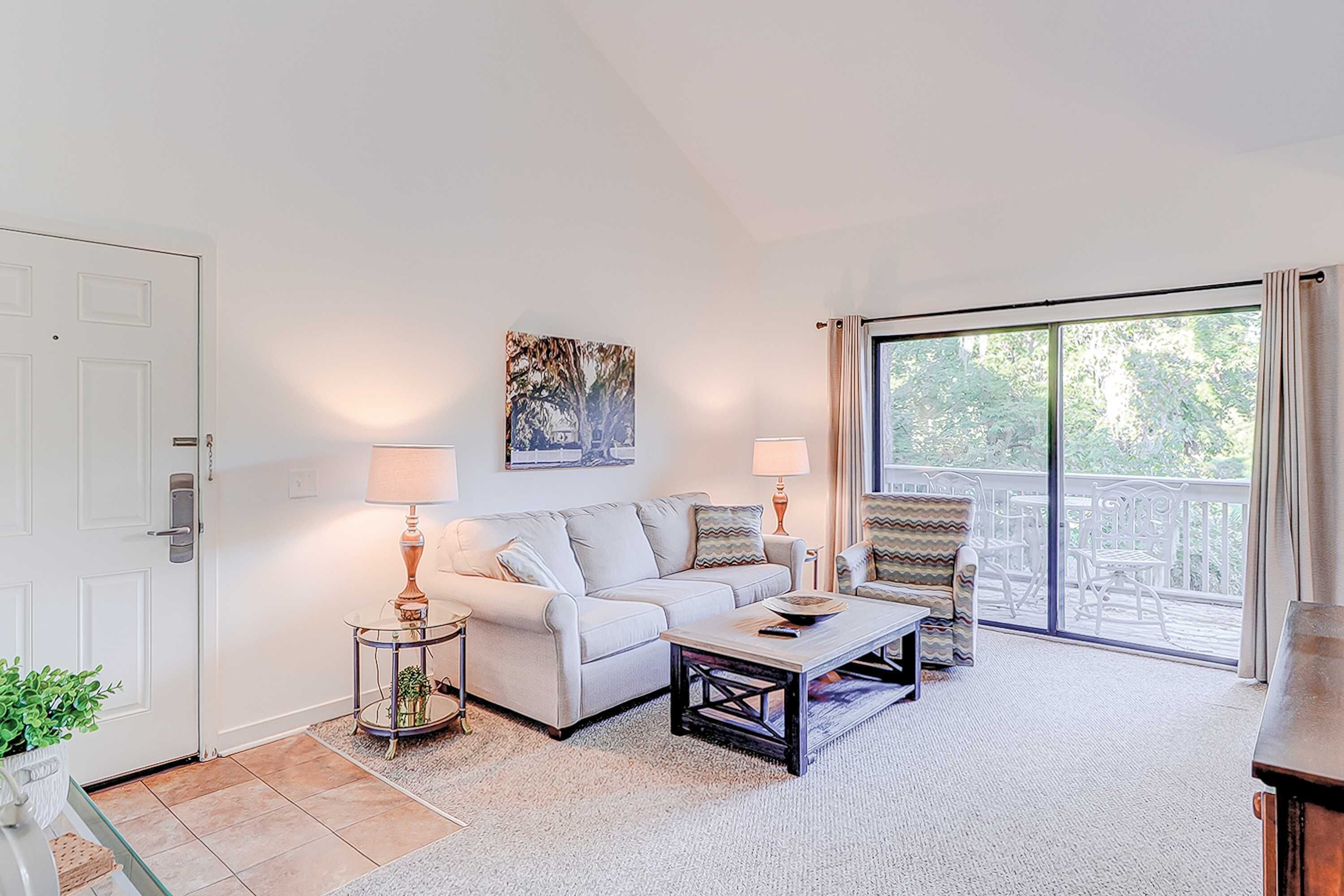 A living room with a sofa, armchair, coffee table, and a painting on the wall.