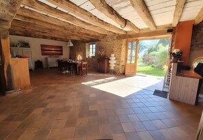 Ein geräumiges Zimmer mit hohen Decken, einem Essbereich, einer Küche und einem großen Fenster mit Blick ins Freie.