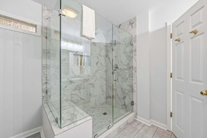 A glass-enclosed shower with marble walls, a white door with brass handles, and a white tiled floor. - Updated all-suite tennis villa with W/D, pool, screened porch - near beach (Hilton Head)