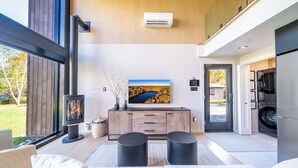 Un salón moderno con chimenea, televisor y vistas al exterior.
