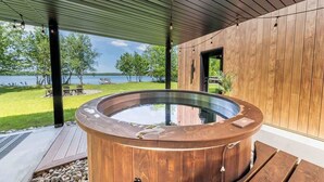 Un jacuzzi bajo una pérgola de madera con vista a un lago.