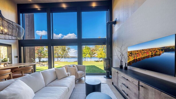 Una sala de estar moderna con un televisor grande, un sofá y vistas a un lago.