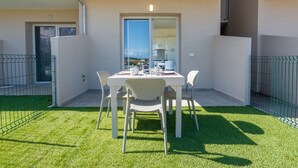 A balcony with a table and chairs, a view of the city, and a door leading to an interior space. - Affittimoderni Castelsardo - White Breeze (Castelsardo)