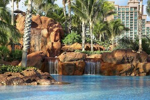 Ein Resort mit Pool, Palmen und einem Wasserfall.