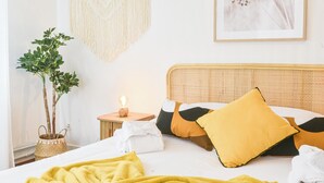 A neatly made bed with a yellow blanket, a bedside lamp, and a potted plant. - Rock in Share - Bianca – 2-Bedroom Apartment with Parking Included & Tram (Strasbourg)
