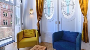 A room with two sofas, a wooden table, and a door with stained glass windows. - La Pépite Place Mondon pour voir le PAPE du balcon (Metz)