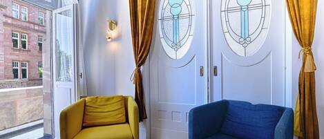 A room with two sofas, a wooden table, and a door with stained glass windows.