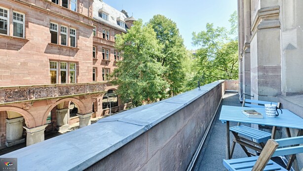 A balcony with a view of a historic building, a stone bridge, and lush trees. - La Pépite Place Mondon pour voir le PAPE du balcon (Metz)