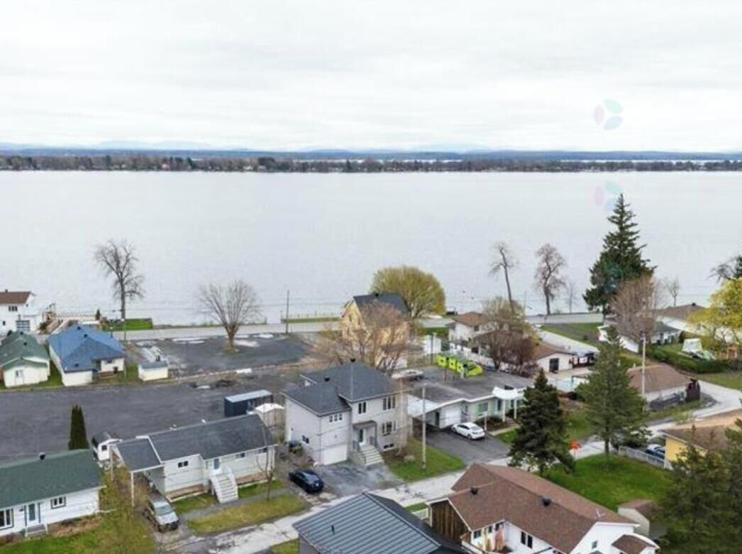 Un quartier résidentiel avec des maisons, un parking et une étendue d’eau en arrière-plan.