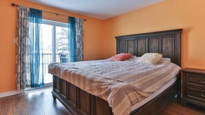 Quarto com cama de madeira, mesa de cabeceira e janela com cortinas.