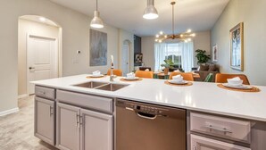 Een moderne keuken met een centraal eiland, inbouwapparatuur en hanglampen.