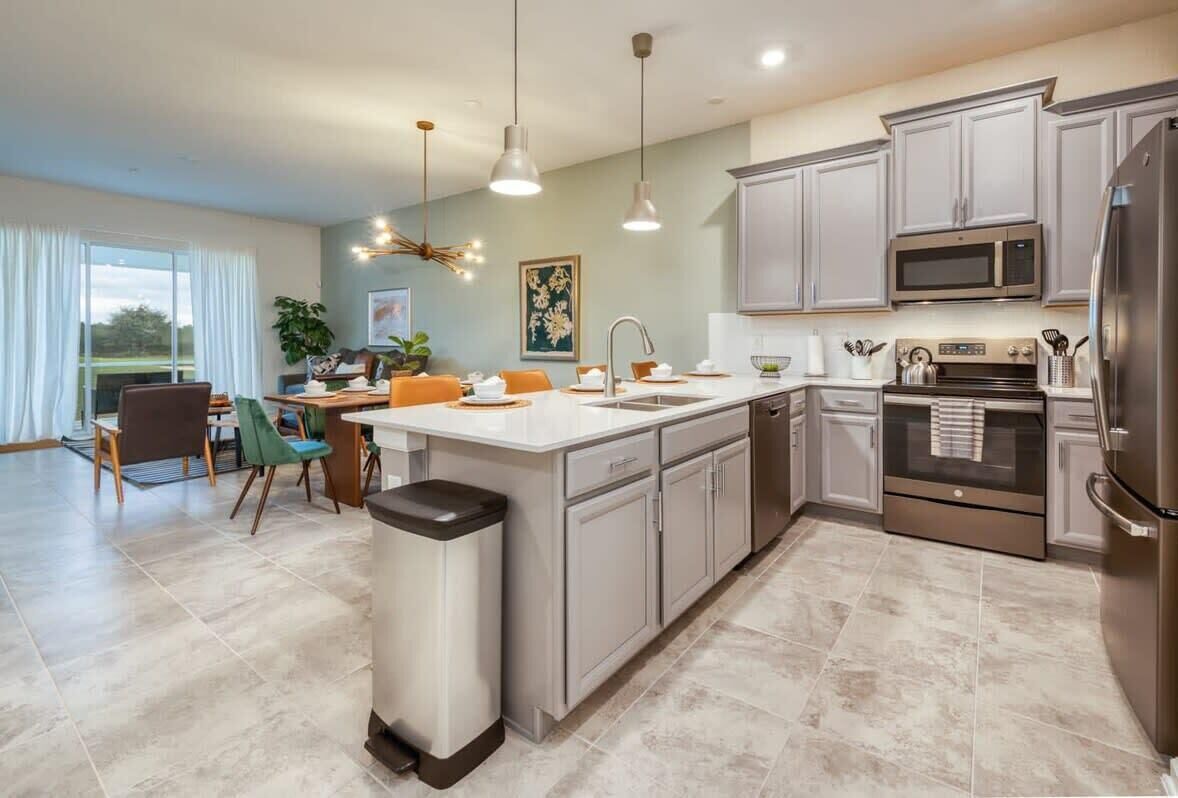 A modern kitchen with a central island, stainless steel appliances, and a dining area with a view.