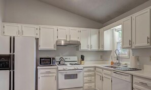 A kitchen with white cabinets, a microwave, stove, oven, and a window. - Charming 3BR Station Home - Fast WiFi, Deck & Parking! (Woodstock)