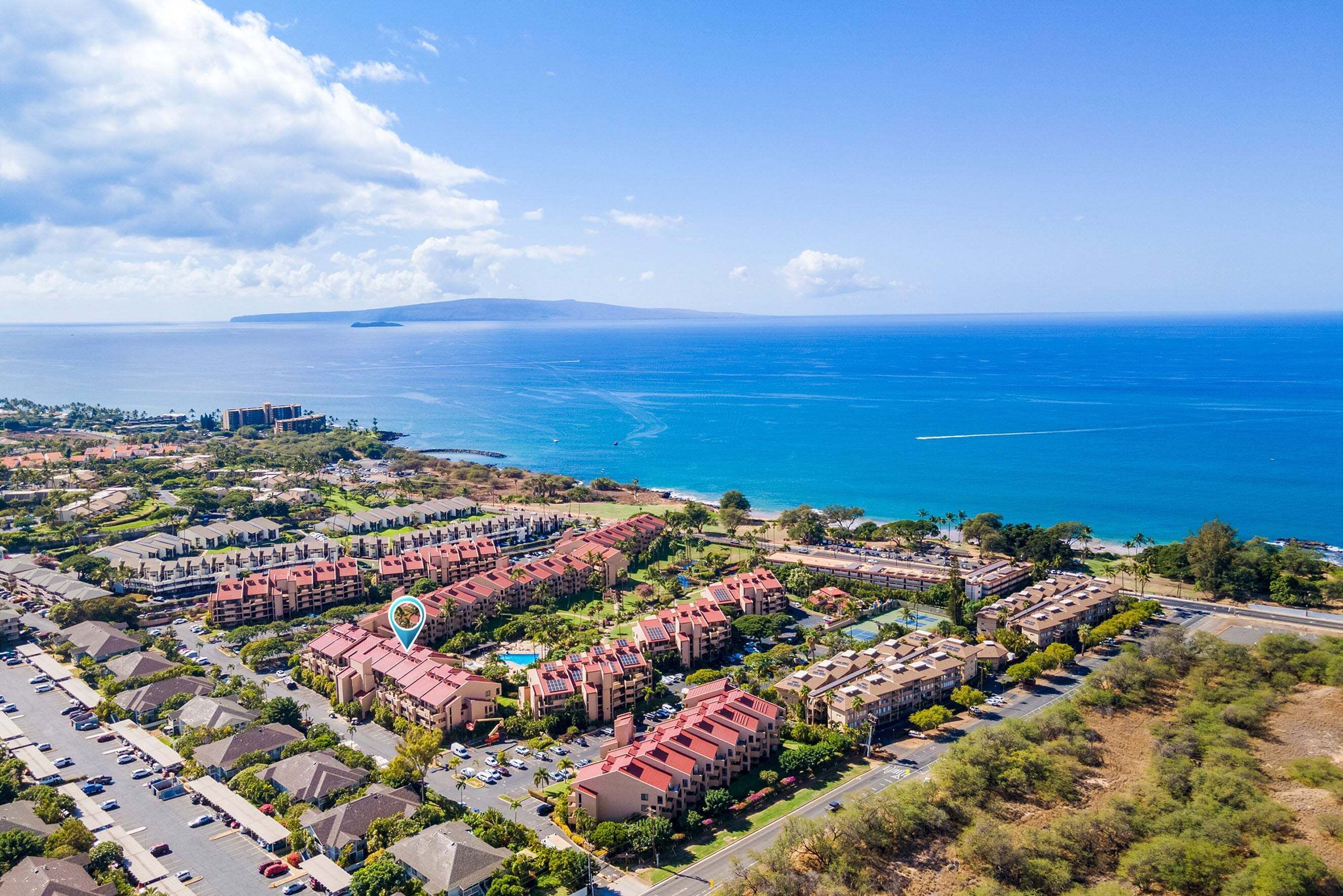 A coastal resort with multiple buildings, a parking lot, and a view of the ocean.