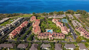 An aerial view of a coastal hotel with multiple buildings, a swimming pool, and a view of the ocean. - Kamaole Sands 5-210 - Stunning 1br/2ba, King Bed, Center-cut Bldg 5, AC, Wi-fi (Kihei)