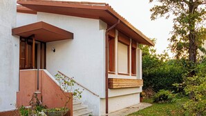 A building with a white exterior, a wooden staircase, and a small garden area.