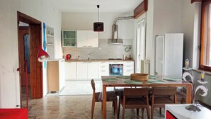 A modern kitchen with white cabinets, a dining table with chairs, and a red pendant light.
