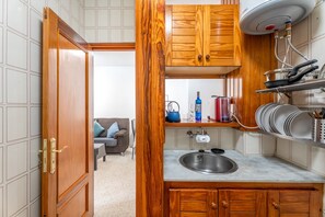 Eine kleine Küche mit Holzausstattung, einem integrierten Spülbecken und einer kompakten Arbeitsfläche.