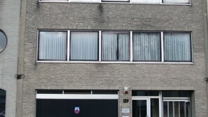 A multi-story building with a garage door, a fire hydrant, and a number '139' on the facade.