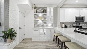 Una cocina moderna con armarios blancos, un salpicadero de baldosas tipo espiga y una isla central con taburetes.