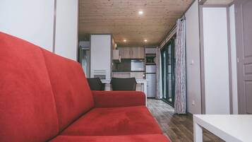 A compact living space with a red sofa, a kitchenette, and a dining area.